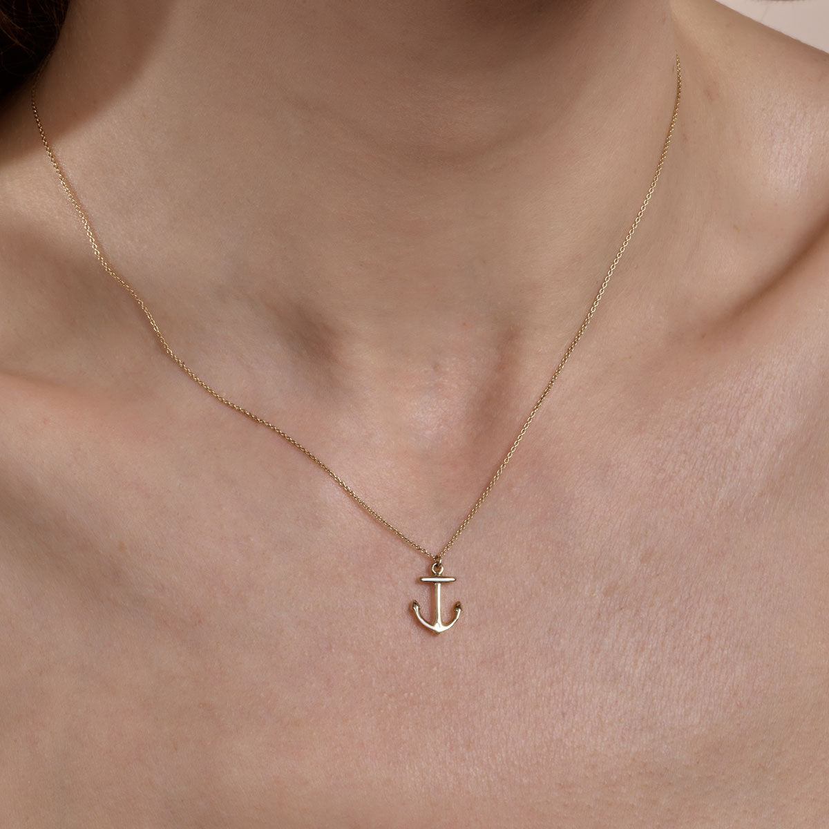 Gold anchor necklace on woman's neck - dainty nautical layering necklace