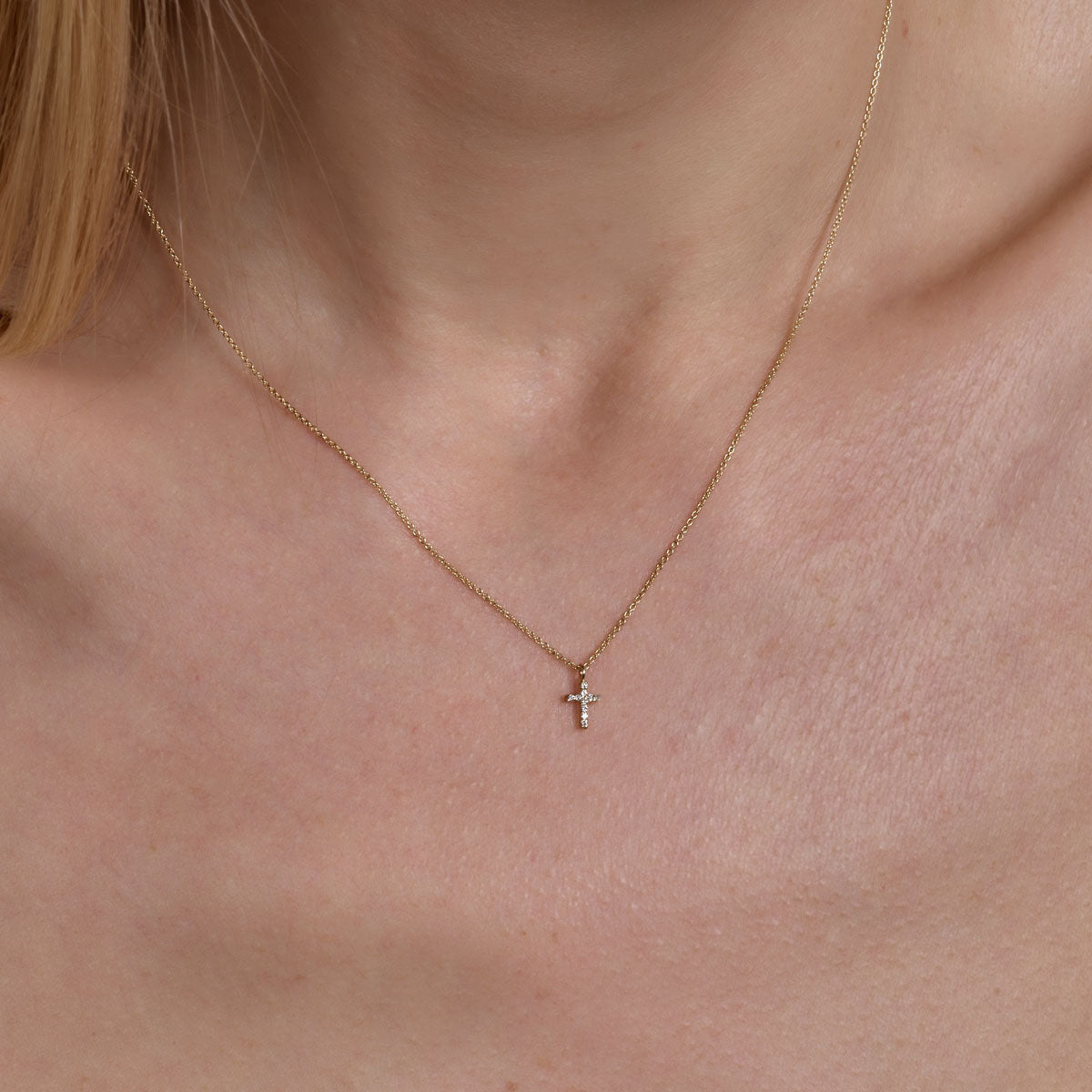 Gold diamond cross necklace on neck - delicate faith-inspired layering necklace