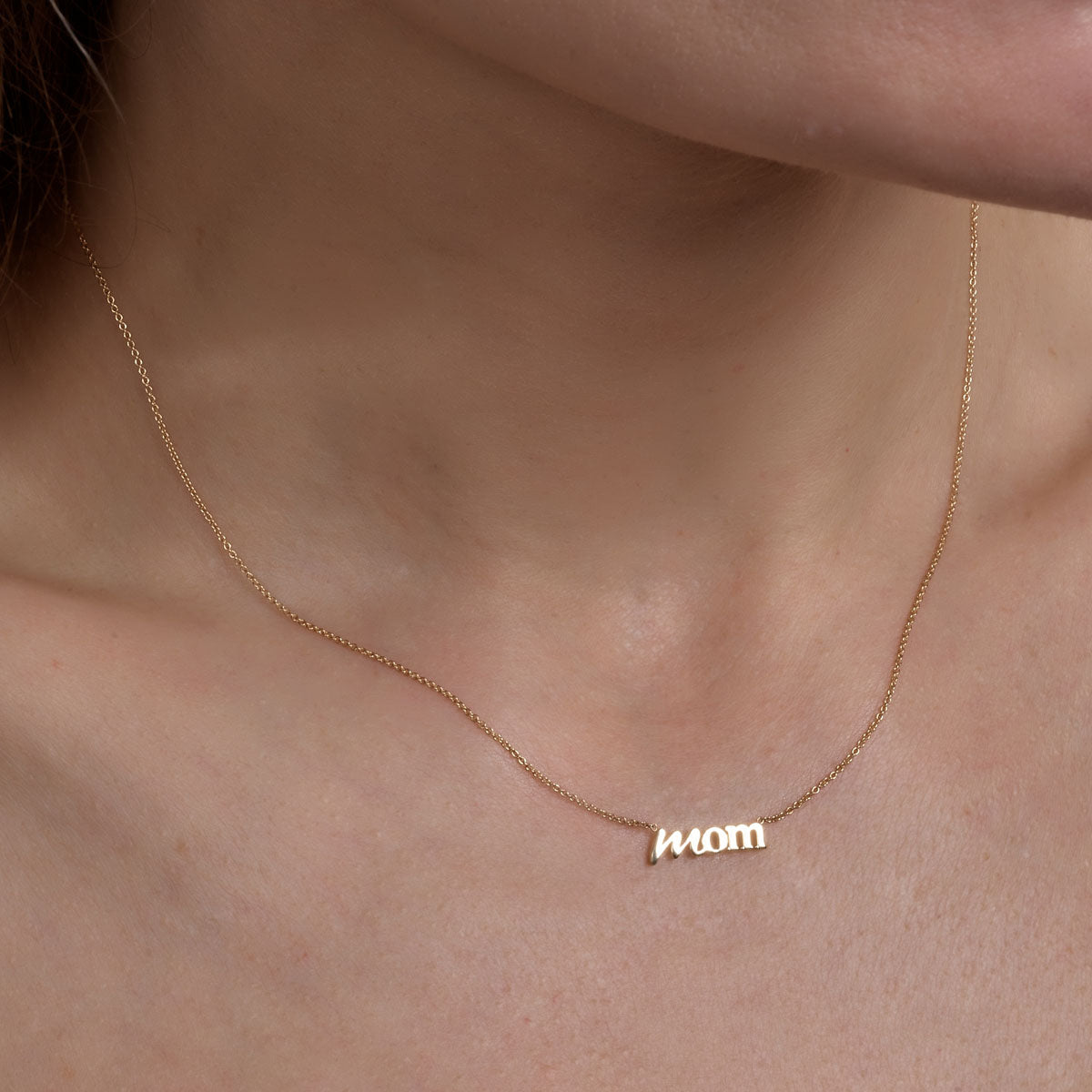 Gold 'Mom' necklace - personalized sentimental jewelry on woman's neck