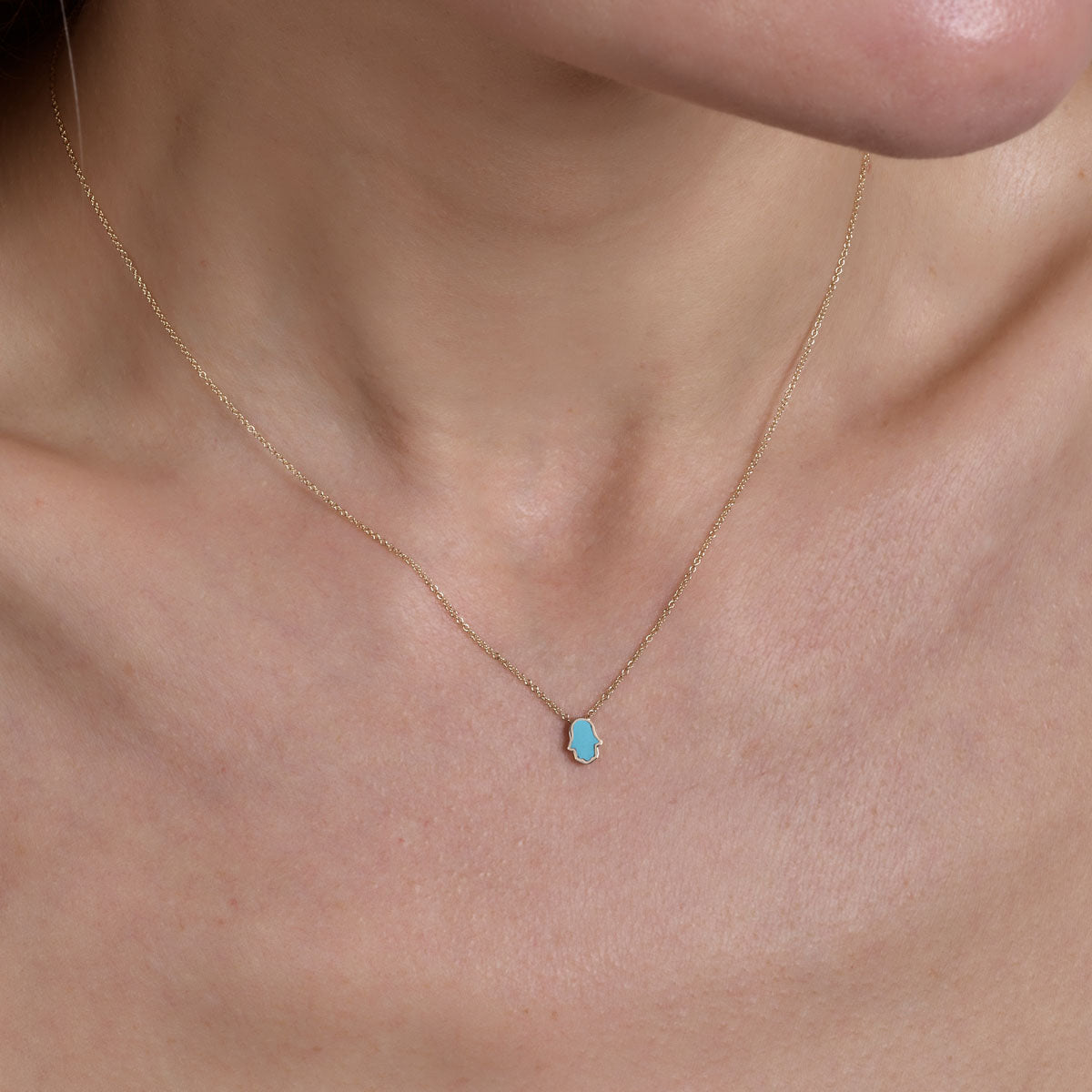 gold turquoise hamsa necklace on neck