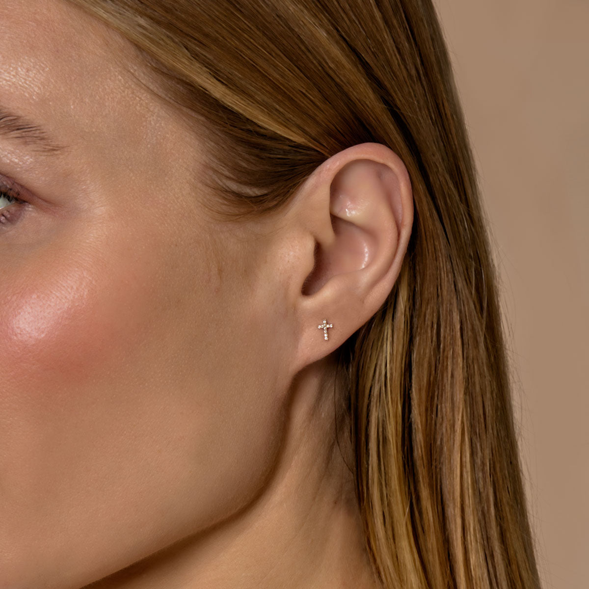 model wearing tiny diamond cross earrings