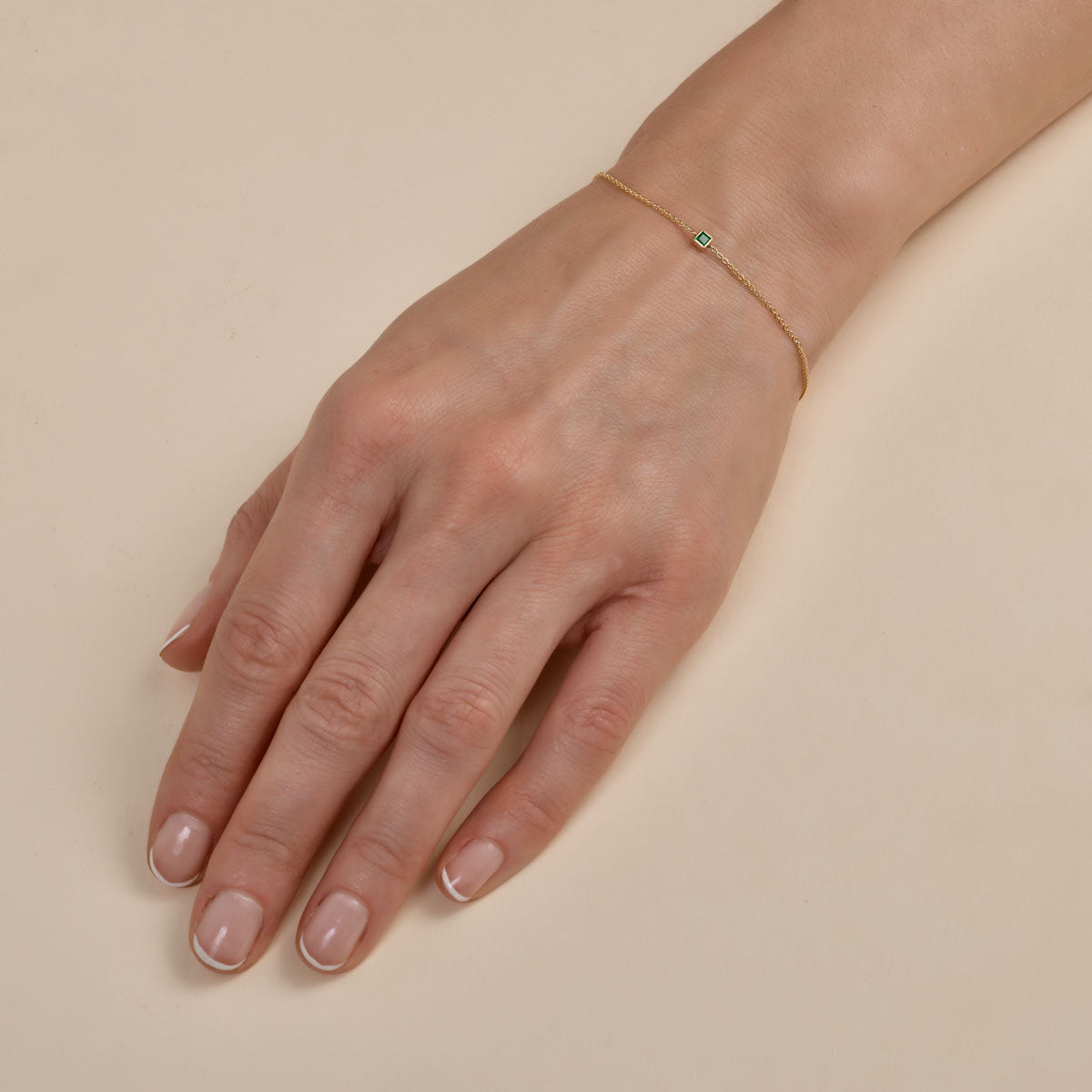 Dainty gold bracelet with square-cut sapphire - delicate luxury on woman's wrist